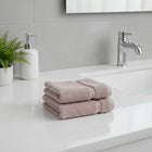 Stack of bamboo hand towels on a bathroom counter with a sink and faucet in the background.