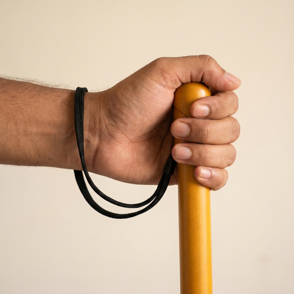 Bamboo Safety Stick gripped in hand with the wrist strap on the wrist, showing scale