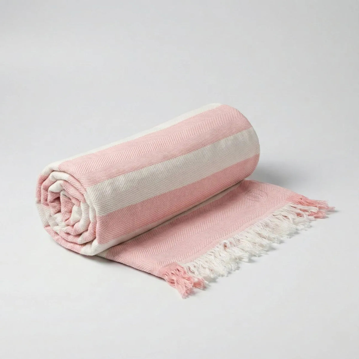 Bamboo Bath Towel rolled in soft pink with cream stripes and fringes for a stylish bathroom accent.