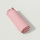 Bamboo Bath Towel rolled up in soft pink color, featuring a herringbone pattern and fringe edges.