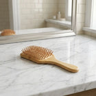 Bamboo hairbrush on a marble countertop with a mirror in the background