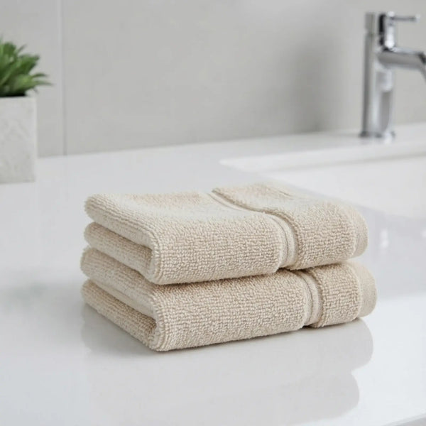 Stack of beige color bamboo hand towels on a white surface with a blurred bathroom background