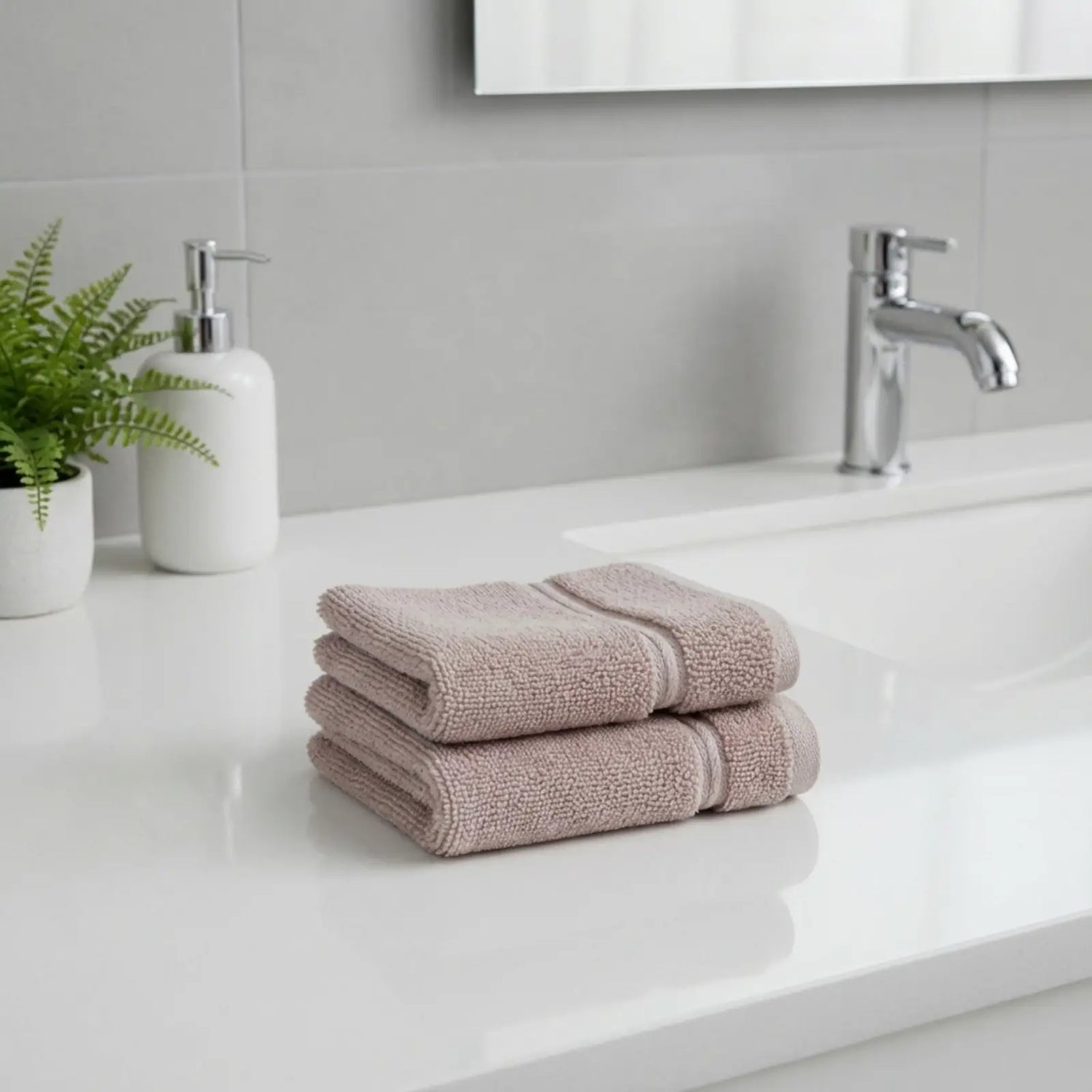 Stack of bamboo hand towels on a bathroom counter with a sink and faucet in the background.