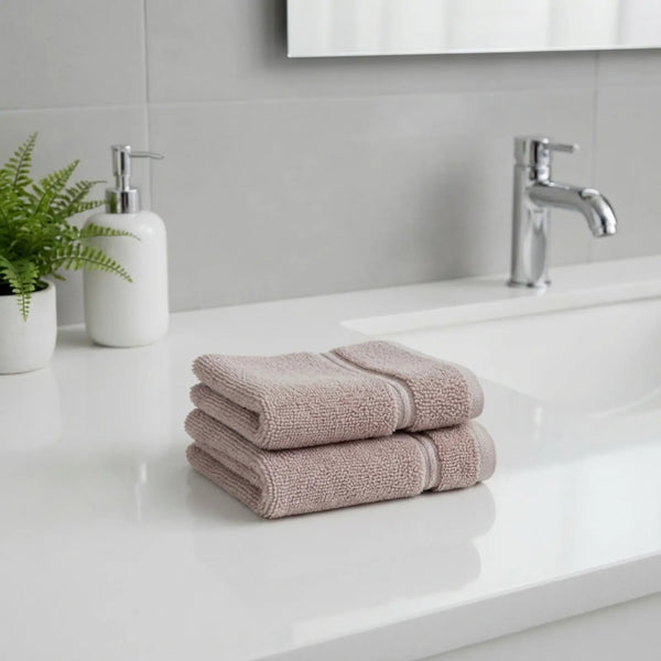 Stack of bamboo hand towels on a bathroom counter with a sink and faucet in the background.