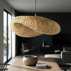 Woven bamboo pendant light hanging above a table in a modern living room.