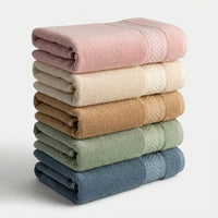 Stack of folded bamboo bath towels in various colors on a light background