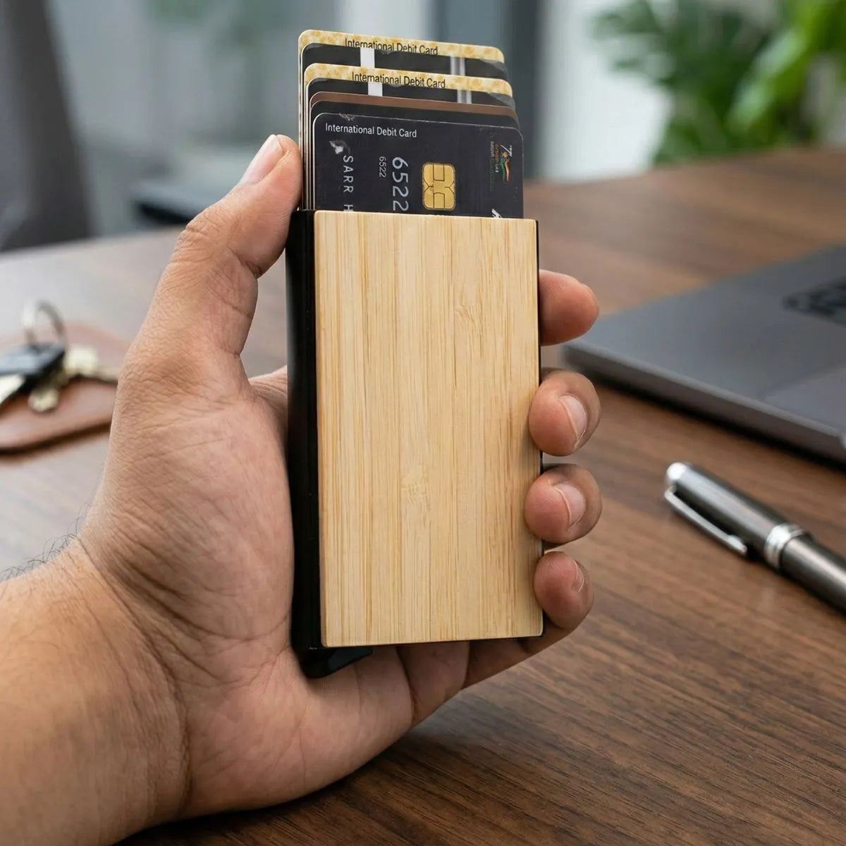 Bamboo pocket card holder held in hand with credit cards visible, showcasing its sleek design and natural finish.