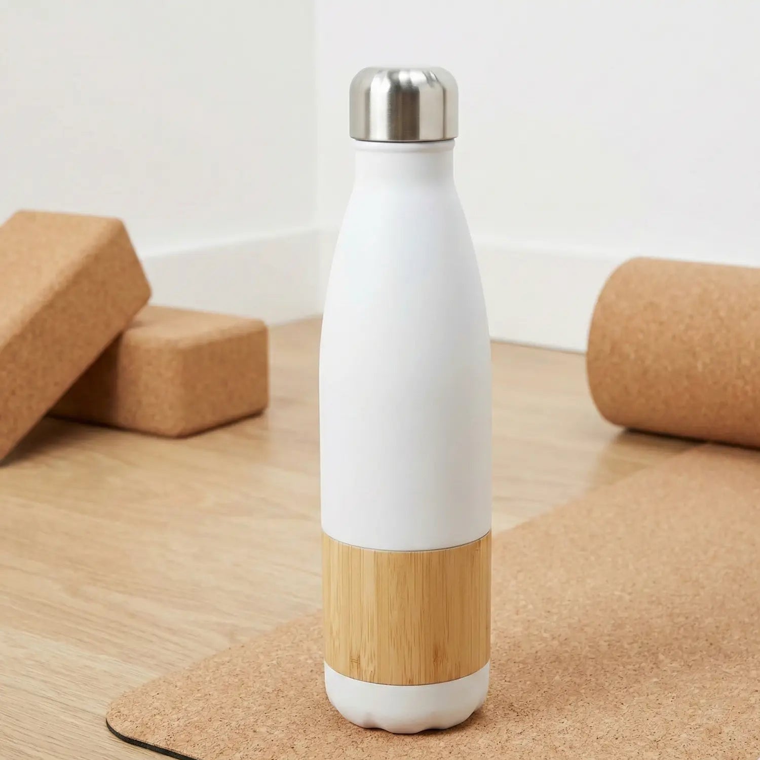 White and bamboo water bottle on a cork surface with yoga blocks in the background