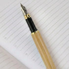 Close-up of a Premium Bamboo Pen resting on lined paper, showcasing its elegant design and smooth writing tip.