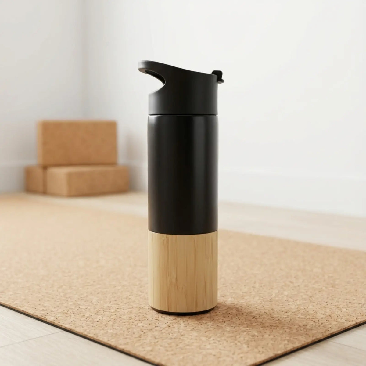 Black and bamboo travel mug on a cork mat with cardboard cork yoga bricks in the background