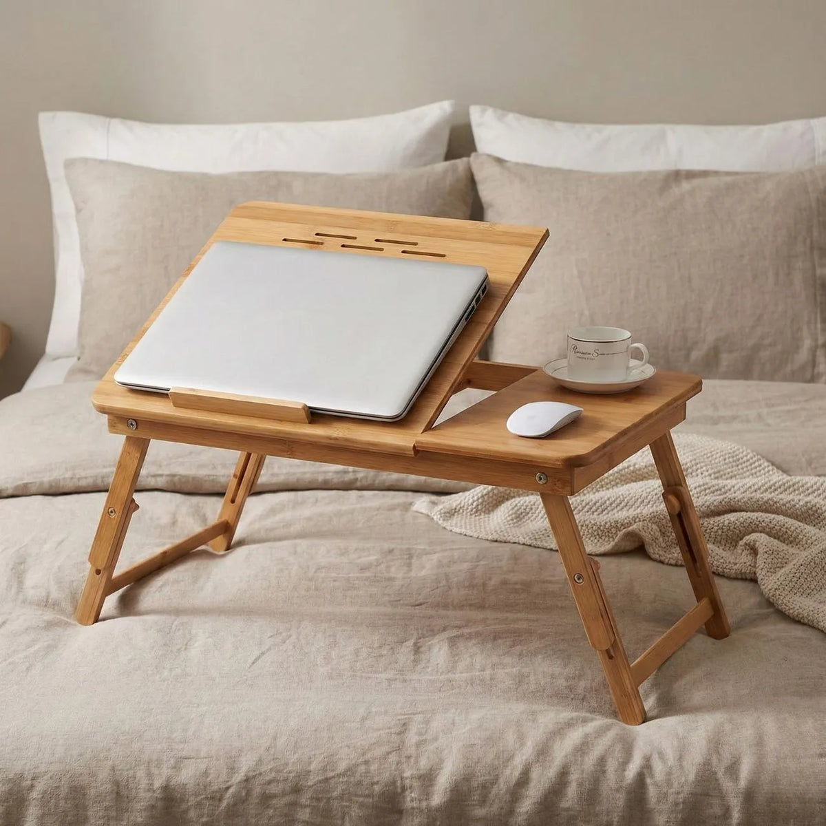 Bamboo Laptop Bed Table with laptop, cup, and mouse on a bed, perfect for working and relaxing.