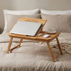 Bamboo Laptop Bed Table with laptop, cup, and mouse on a bed, perfect for working and relaxing.