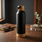 Bamboo Steel Water Bottle on a wooden desk beside a notebook, glasses and eucalyptus