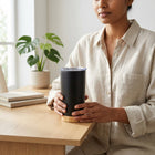 Bamboo Tumbler held in both hands — shows scale and bamboo base detail