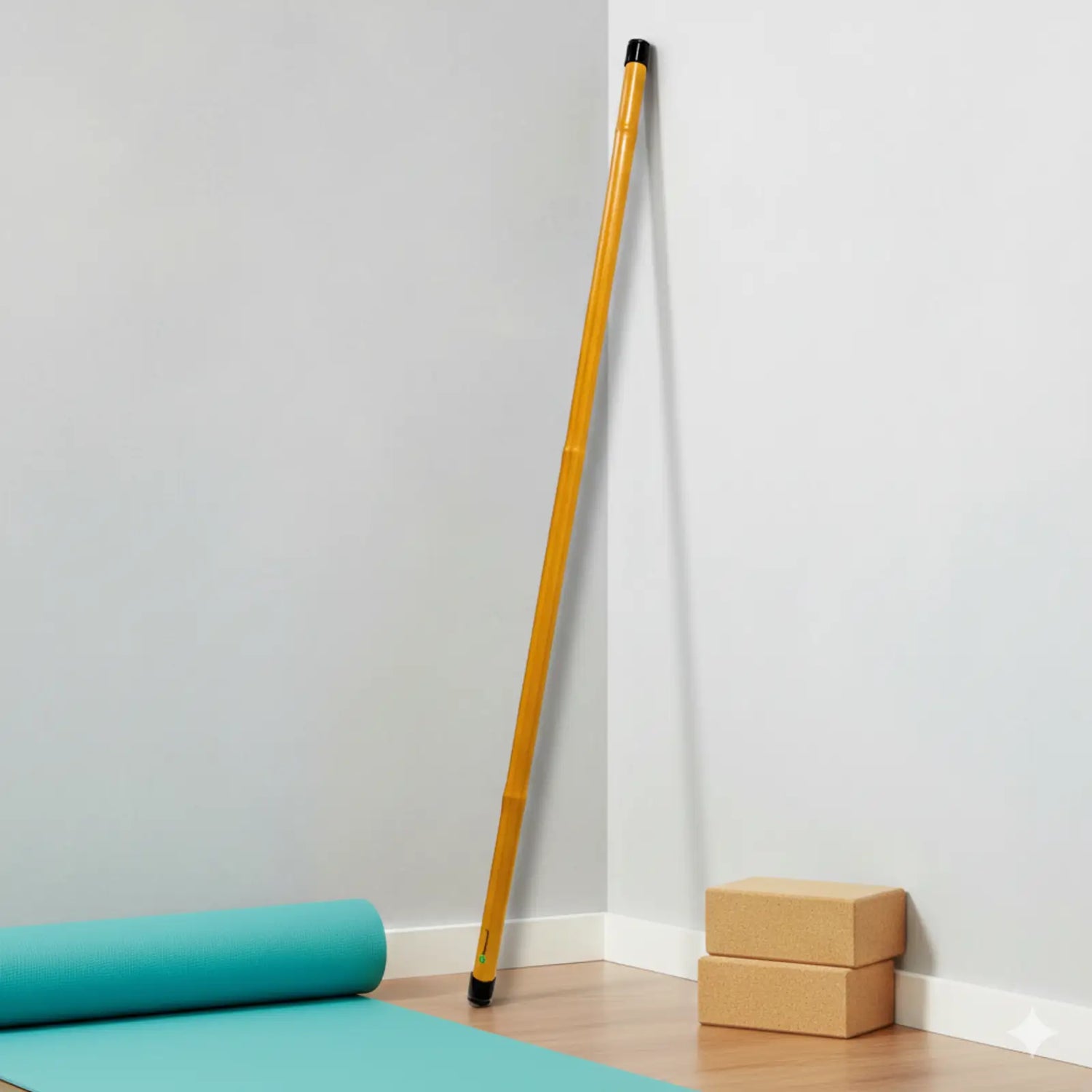 Yoga mat, bamboo fitness stick and cork blocks on a light wood floor against a white wall.