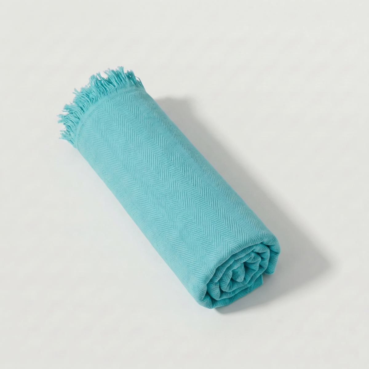 Bamboo Turkish Towel rolled in solid turquoise, herringbone weave with matching fringe.