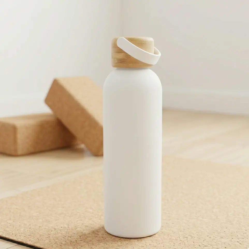 White water bottle with a bamboo cap on a yoga mat