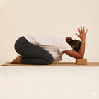 Person practicing yoga with a Cork Yoga Block for support during a pose on a yoga mat.